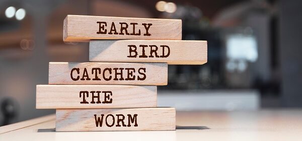 Wooden blocks with words 'Early bird catches the worm'.